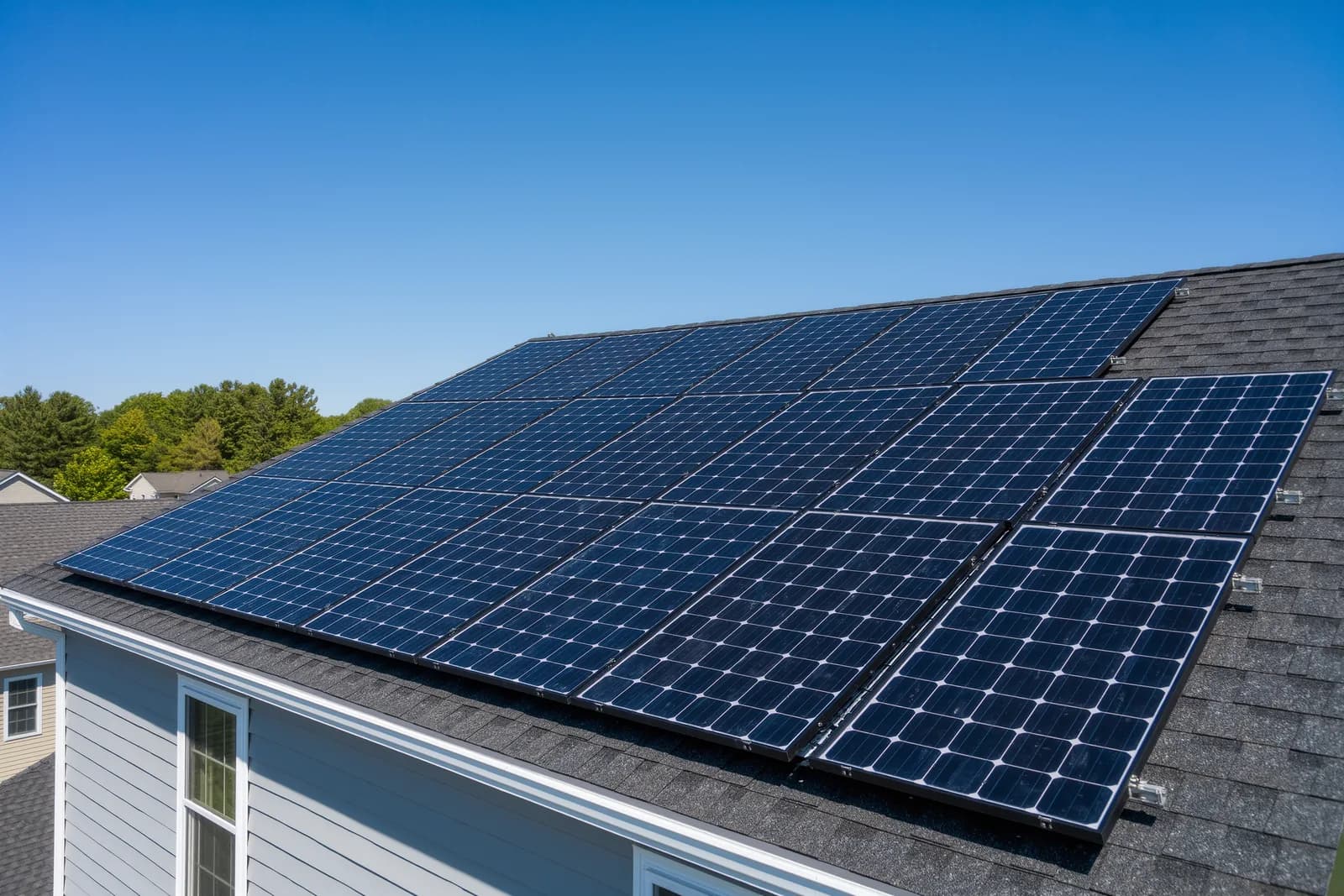 Black solar panels installed on a dark gray asphalt shingle roof of a suburban Maryland home on a sunny day